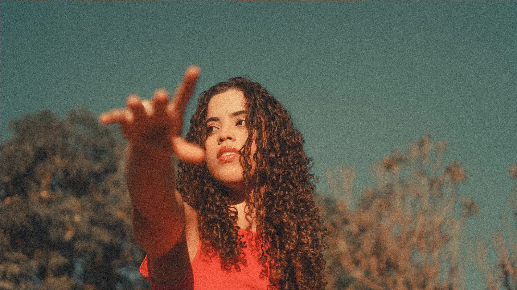 Modelo de vestido vermelho em ensaio fotográfico com o braço estendido