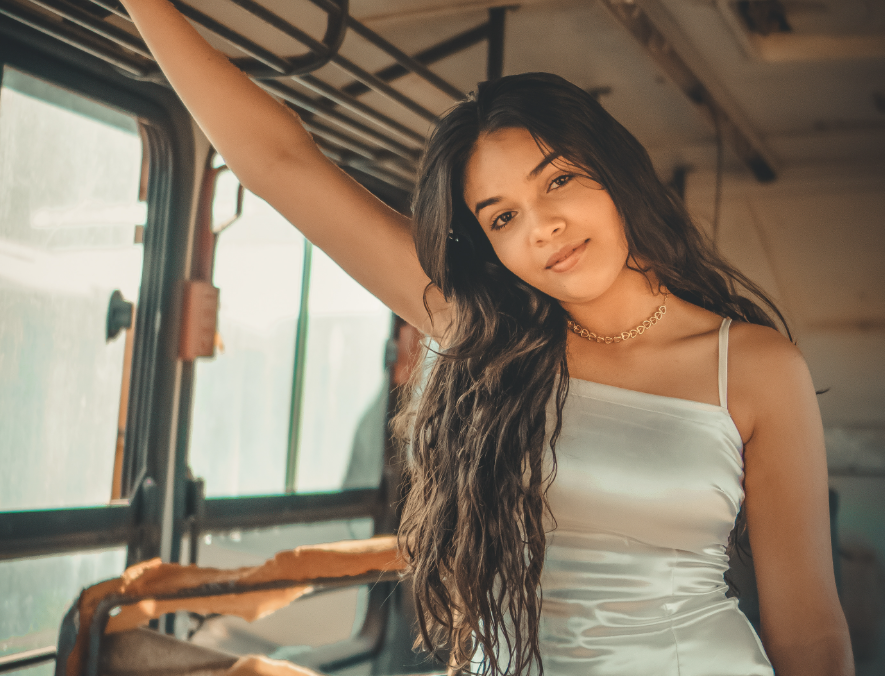 Modelo de vestido branco em ensaio fotográfico dentro de um ônibus vintage
