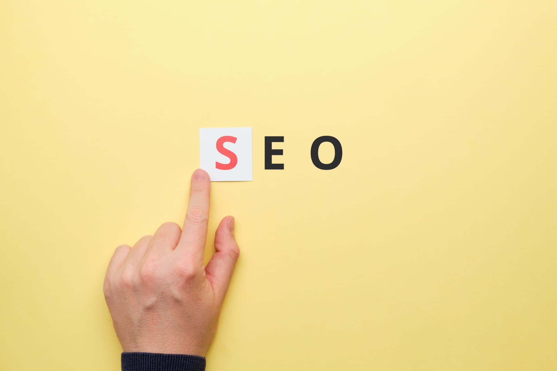 Mão posicionando a letra S na palavra SEO