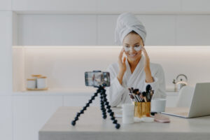Mulher jovem aplicando produto de skincare da marca Rhode no rosto em um ambiente minimalista e iluminado representando rotina de cuidados com a pele saudável e estética clean