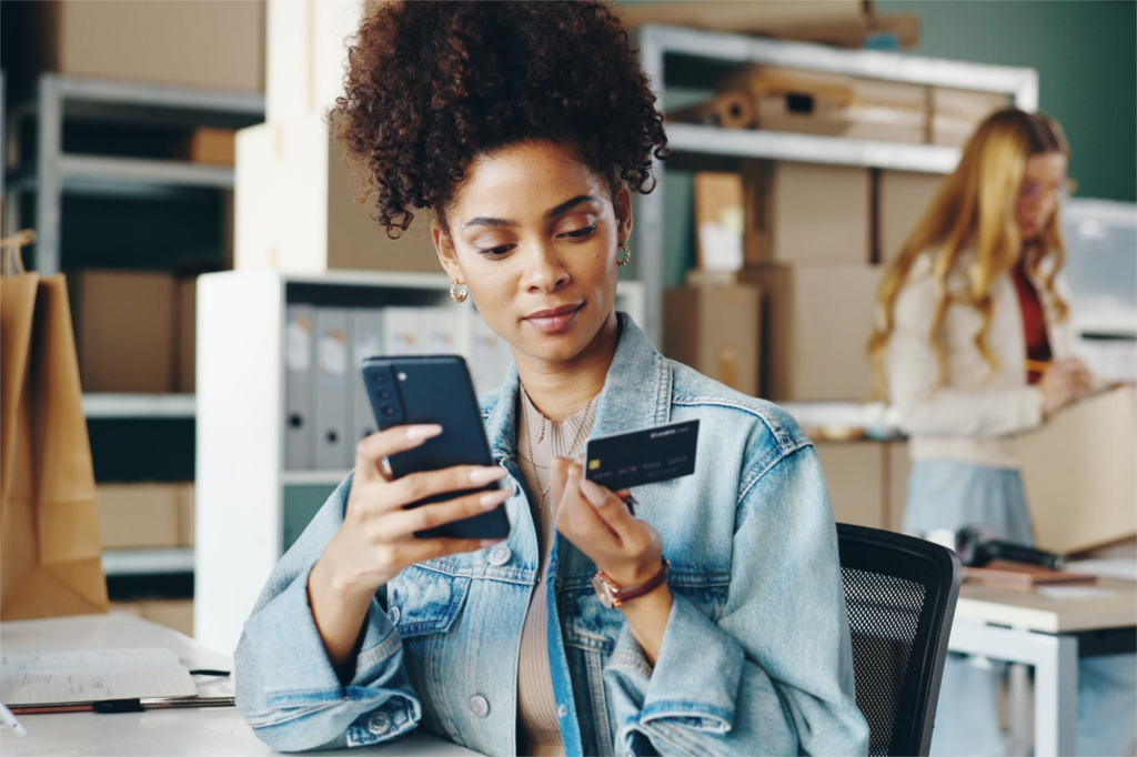 image82375 AnonMedia AnonMedia Mulher usando o celular e um cartão de crédito em um ambiente de trabalho simbolizando o uso de dados CRM personalização e estratégias omnichannel que impulsionam o faturamento no varejo como no case de sucesso da Renner