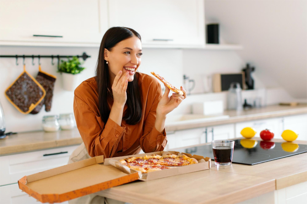 Cliente sorrindo comendo pizza em casa durante delivery, representando a experiência da Papa Johns e o consumo local impulsionado por marketing orientado a dados.